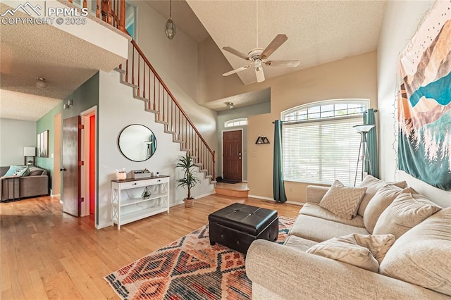 living room featuring ceiling fan, wood-type flooring, high vaulted ceiling, and a textured ceiling