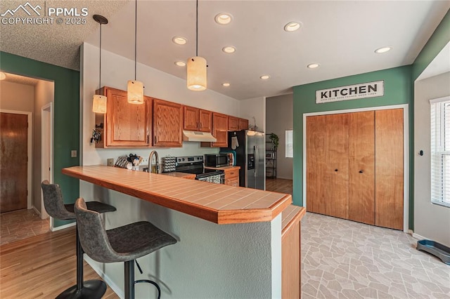 kitchen with hanging light fixtures, a breakfast bar area, stainless steel appliances, and kitchen peninsula