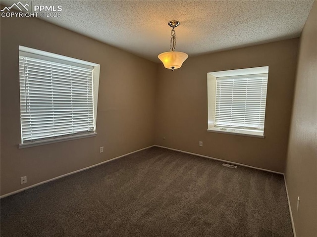 spare room with a textured ceiling and dark colored carpet