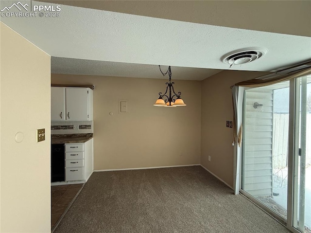 unfurnished dining area with an inviting chandelier, a textured ceiling, and dark carpet