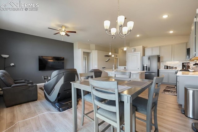 dining space featuring ceiling fan with notable chandelier and light hardwood / wood-style floors