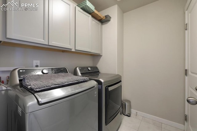 laundry area featuring separate washer and dryer, light tile patterned floors, and cabinets