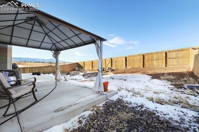 snow covered patio with a mountain view and a gazebo