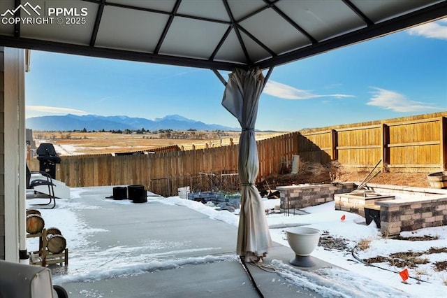 yard covered in snow featuring a mountain view