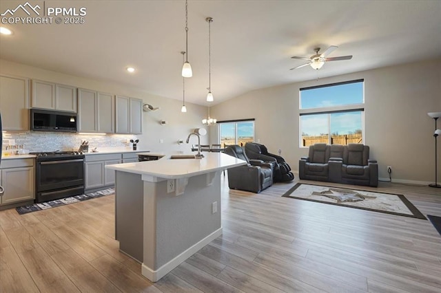 kitchen featuring gray cabinetry, black range oven, an island with sink, pendant lighting, and light hardwood / wood-style floors