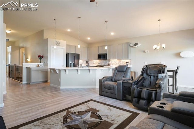 living room with high vaulted ceiling, a chandelier, and light hardwood / wood-style floors