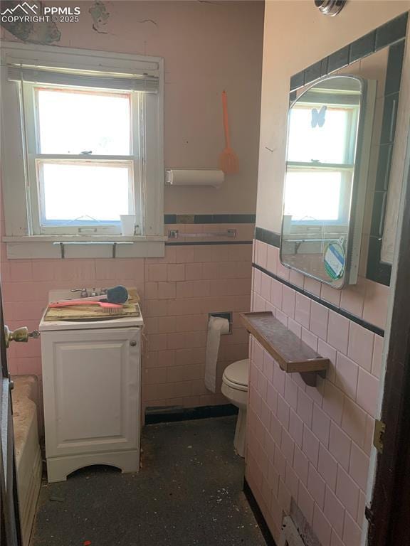 bathroom with toilet, washer / dryer, and tile walls