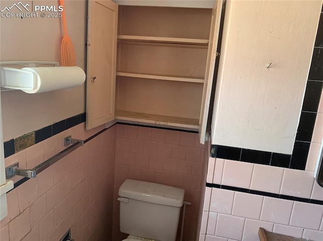 bathroom featuring toilet and tile walls