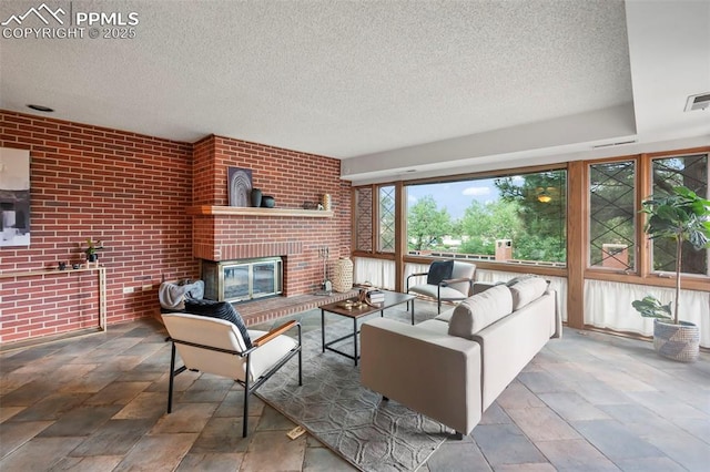 living room featuring brick wall, a brick fireplace, and a textured ceiling