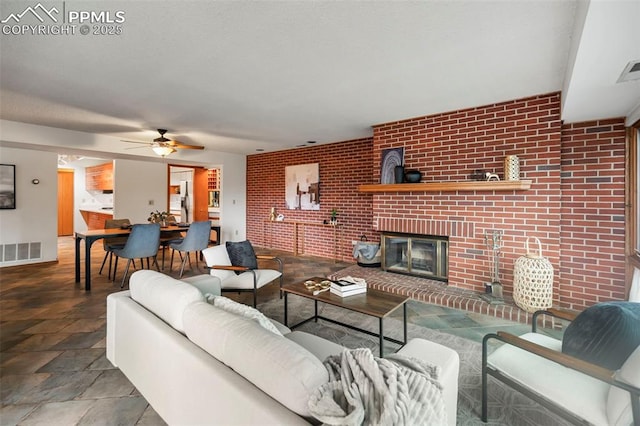 living room with brick wall, a brick fireplace, and ceiling fan