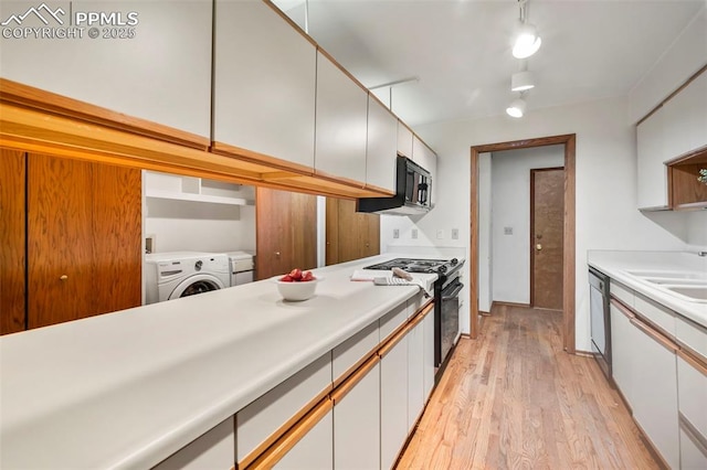 kitchen featuring sink, light hardwood / wood-style flooring, black appliances, white cabinets, and washer / clothes dryer