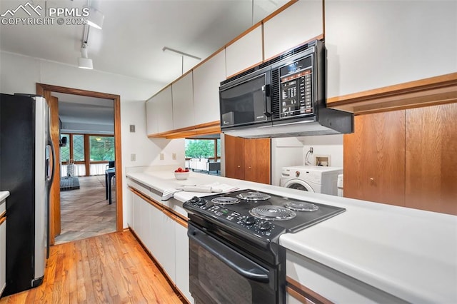 kitchen with washer / clothes dryer, white cabinetry, black appliances, plenty of natural light, and light wood-type flooring