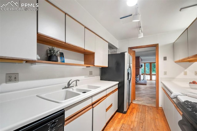 kitchen featuring black dishwasher, sink, white cabinets, stove, and light hardwood / wood-style flooring