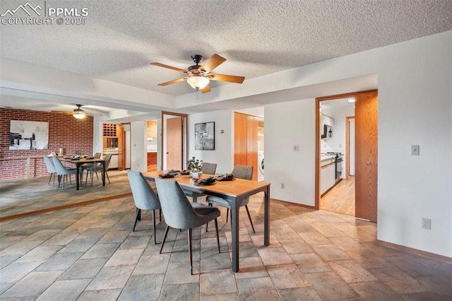 dining area with washer / clothes dryer, brick wall, a textured ceiling, and ceiling fan