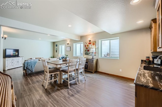 dining room featuring beam ceiling, sink, a textured ceiling, and dark hardwood / wood-style floors