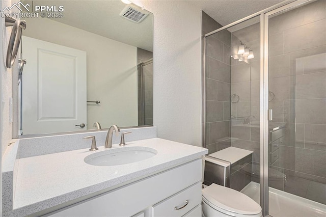 bathroom with vanity, toilet, and a shower with door