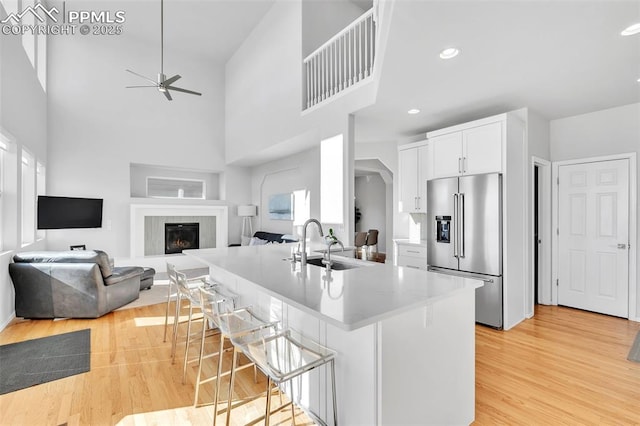 kitchen with white cabinetry, sink, high end refrigerator, a kitchen breakfast bar, and light hardwood / wood-style floors