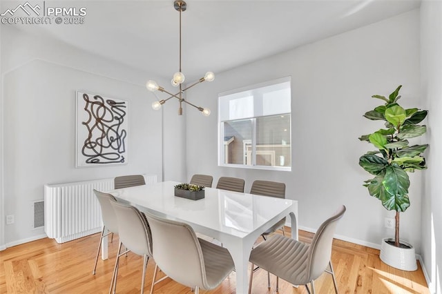 dining area with an inviting chandelier, radiator heating unit, and light hardwood / wood-style floors