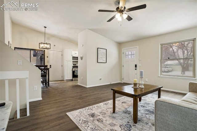 living room featuring dark wood-type flooring, ceiling fan with notable chandelier, and vaulted ceiling