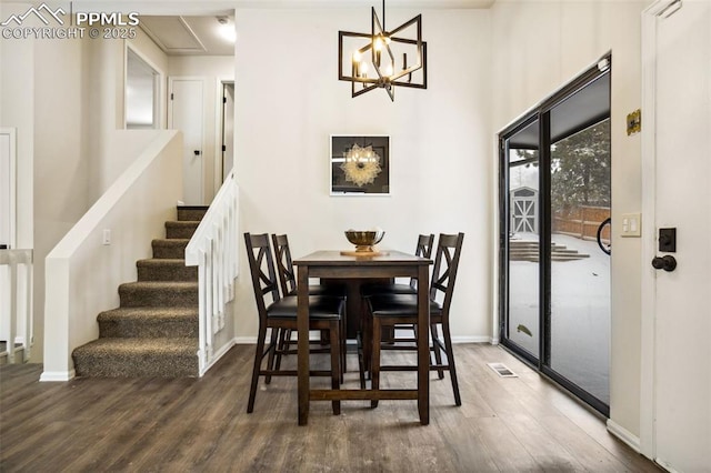 dining space with dark wood-type flooring and an inviting chandelier