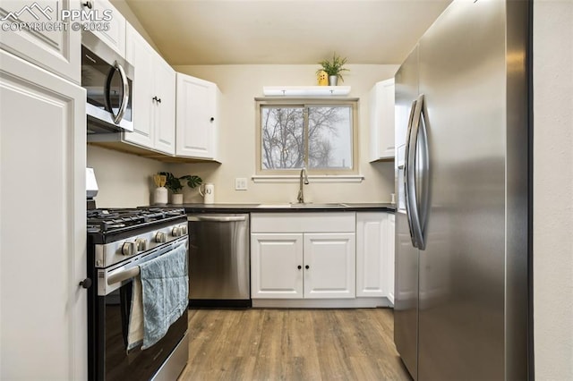 kitchen featuring stainless steel appliances, sink, wood-type flooring, and white cabinets