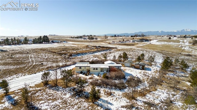 snowy aerial view with a mountain view and a rural view