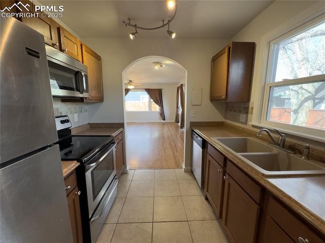 kitchen featuring sink, light tile patterned floors, ceiling fan, stainless steel appliances, and backsplash