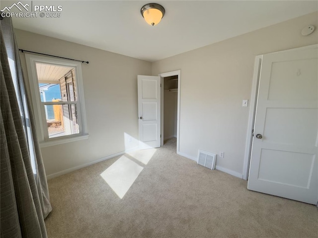 unfurnished bedroom with light colored carpet and a closet