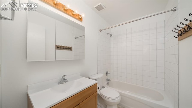 full bathroom featuring vanity, tiled shower / bath combo, and toilet