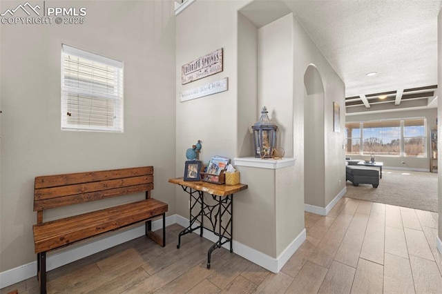 corridor featuring coffered ceiling, beam ceiling, and light hardwood / wood-style flooring