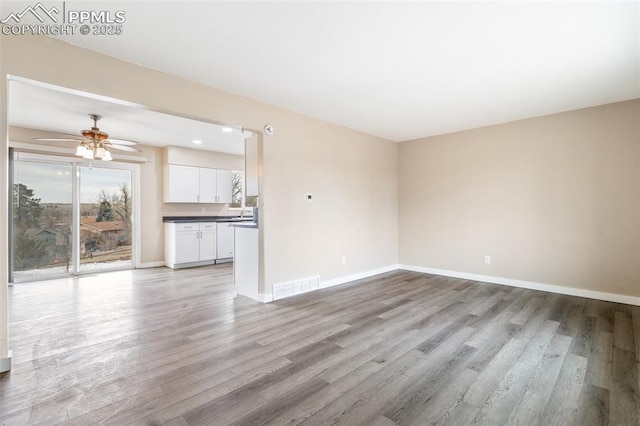 unfurnished living room with ceiling fan and light hardwood / wood-style floors