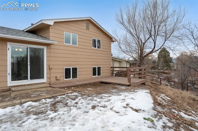 snow covered rear of property with a deck