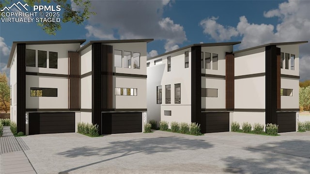 view of front of home featuring driveway, an attached garage, and stucco siding