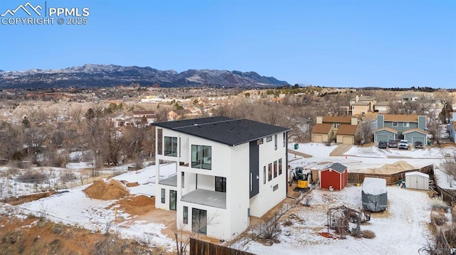 snowy aerial view featuring a residential view and a mountain view