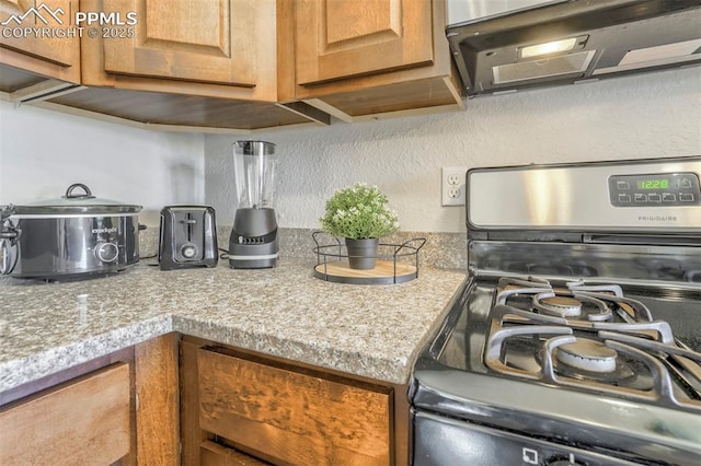 kitchen with range with gas cooktop, light stone countertops, and ventilation hood