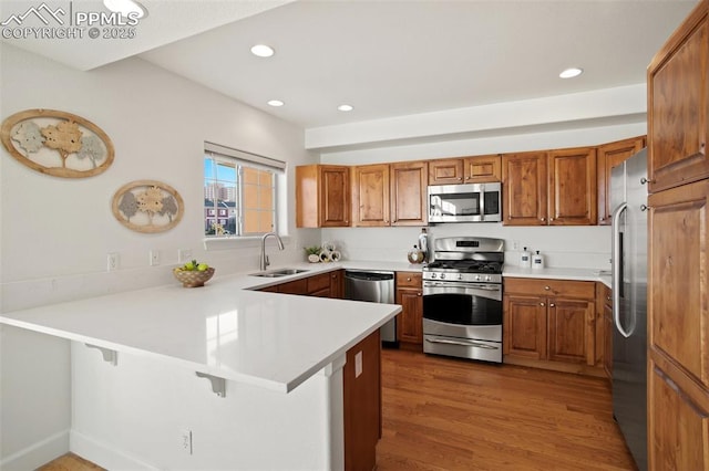 kitchen featuring a breakfast bar, sink, kitchen peninsula, hardwood / wood-style flooring, and stainless steel appliances