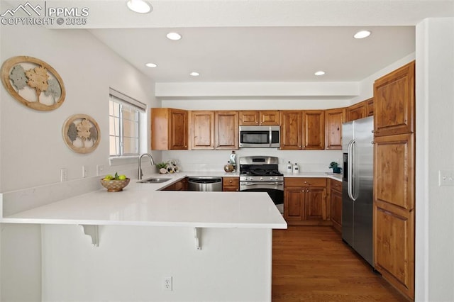 kitchen with sink, a kitchen breakfast bar, kitchen peninsula, and appliances with stainless steel finishes