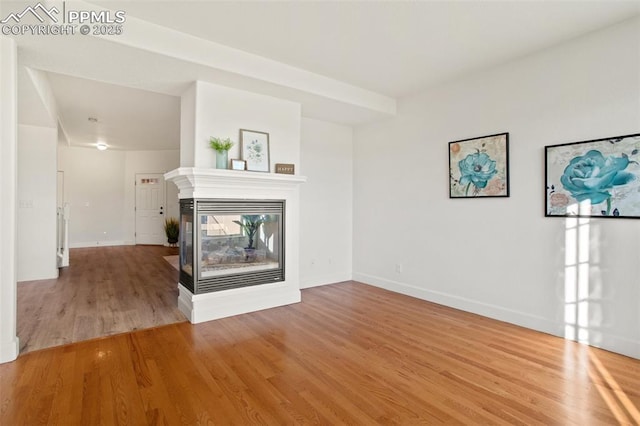 unfurnished living room with hardwood / wood-style flooring and a multi sided fireplace