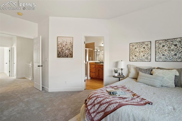 bedroom with ensuite bathroom and light carpet