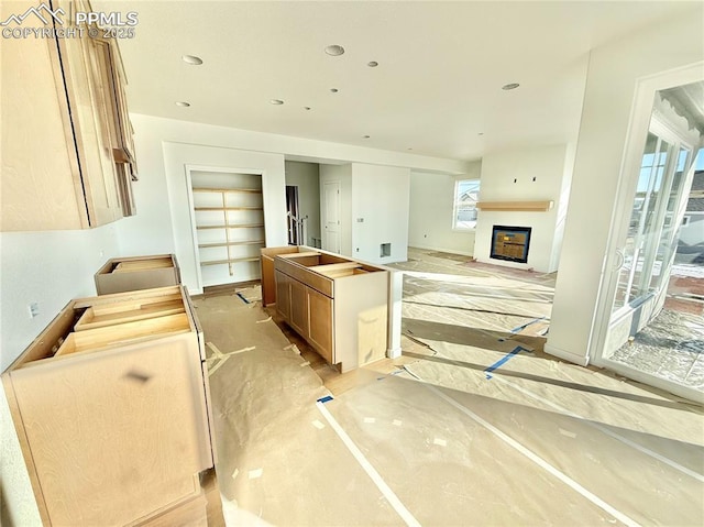 kitchen featuring recessed lighting, an island with sink, and a fireplace