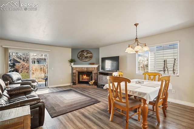 dining area featuring hardwood / wood-style flooring, a brick fireplace, and a chandelier