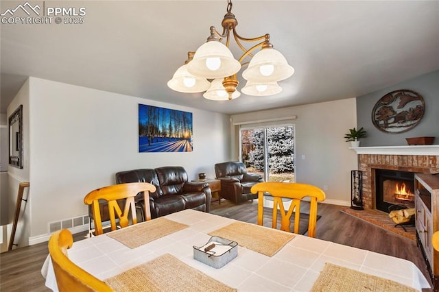 dining area featuring a brick fireplace, dark wood-type flooring, and a notable chandelier