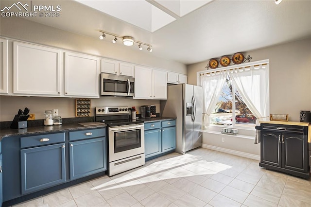 kitchen with blue cabinets, light tile patterned flooring, appliances with stainless steel finishes, and white cabinets