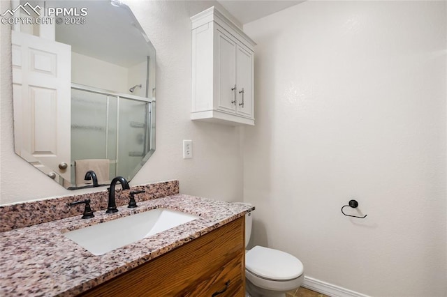 bathroom with a shower with door, vanity, and toilet