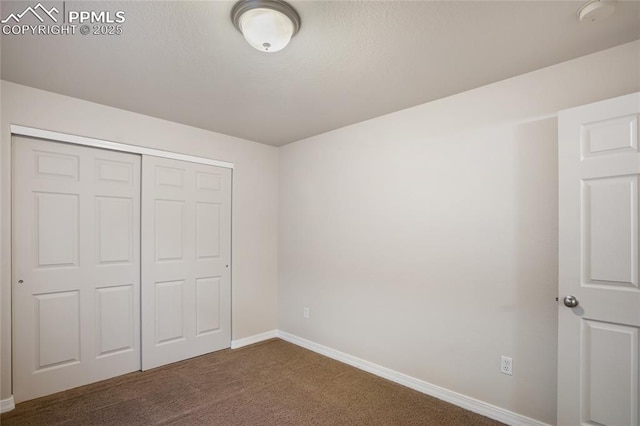 unfurnished bedroom featuring a closet and dark colored carpet