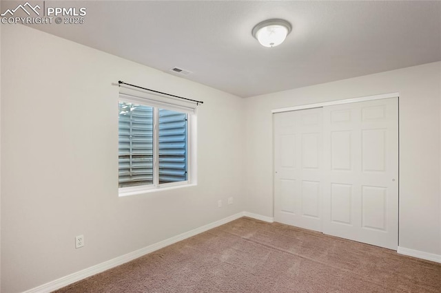 unfurnished bedroom with light colored carpet and a closet