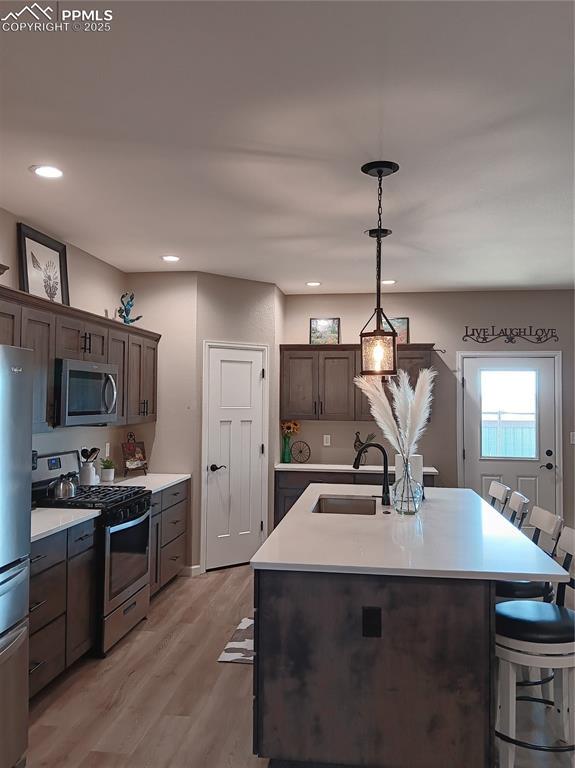 kitchen with pendant lighting, sink, a breakfast bar, appliances with stainless steel finishes, and an island with sink