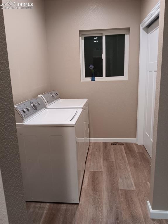 laundry room featuring washer and clothes dryer and light hardwood / wood-style flooring