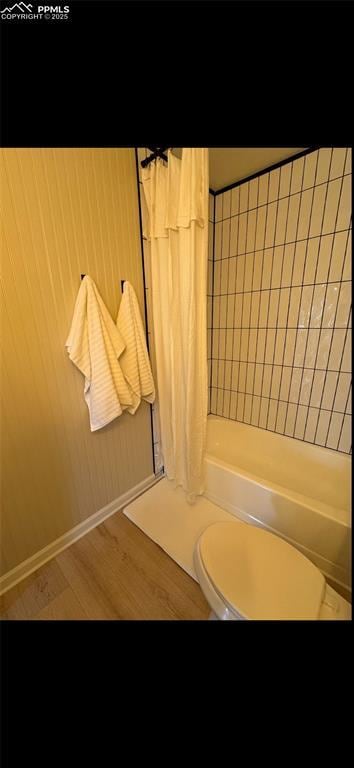 bathroom featuring wood-type flooring, toilet, and shower / bath combo