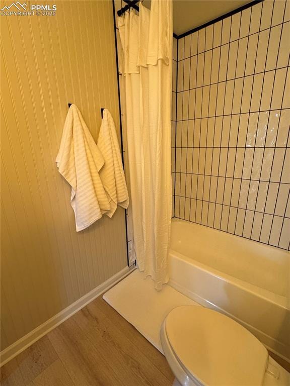 bathroom with shower / tub combo with curtain, wood-type flooring, wooden walls, and toilet